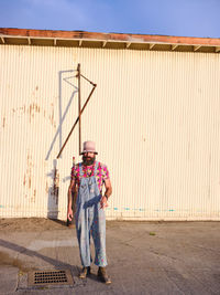 A man dressed in alternative fashions stands in an industrial setting.