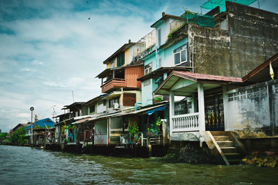 Houses by river against sky in city