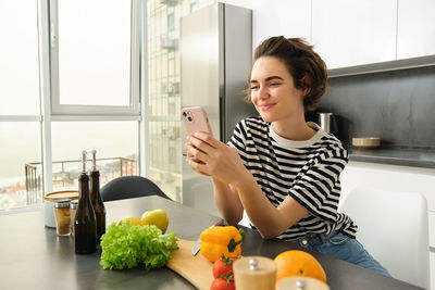 Portrait of young woman using mobile phone at home