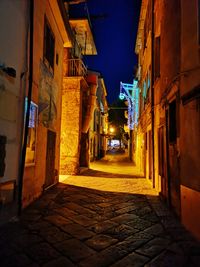 Narrow street amidst buildings in city at night