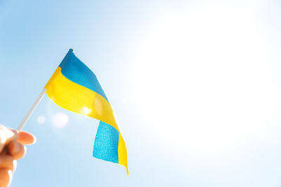 Human hand holding large bicolor yellow blue ukrainian state flag, national symbol fluttering