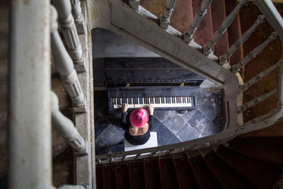 High angle view of woman playing piano by staircase at home