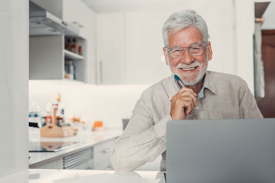 Portrait of man using mobile phone while sitting at home