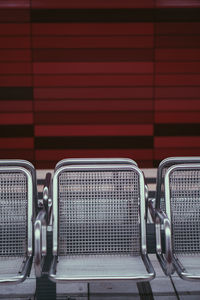 Close-up of empty seats on footpath against wall