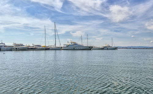 Sailboats moored on sea against sky