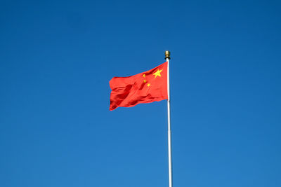 Low angle view of flag against clear blue sky