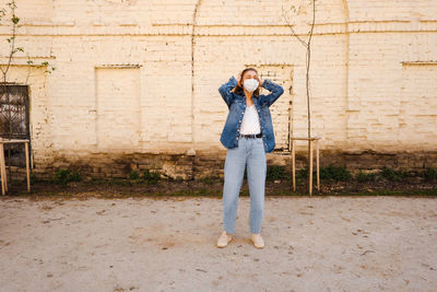 Full length of a woman standing against brick wall