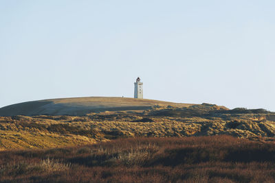 Lighthouse on field against clear sky