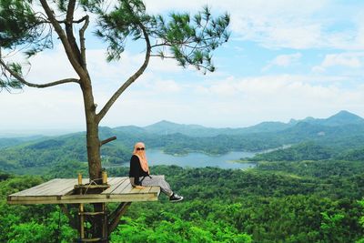 Woman sitting on observation point against mountains