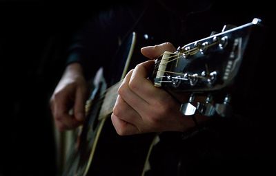 Midsection of man playing guitar