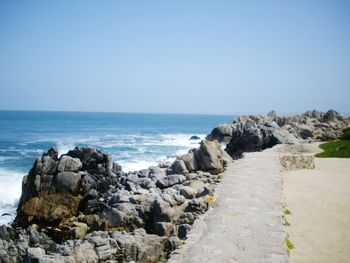 Rocks by sea against clear sky