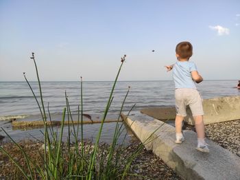 Full length of boy standing in sea against sky