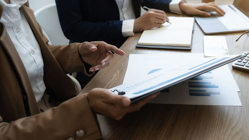 Midsection of business colleagues working on table