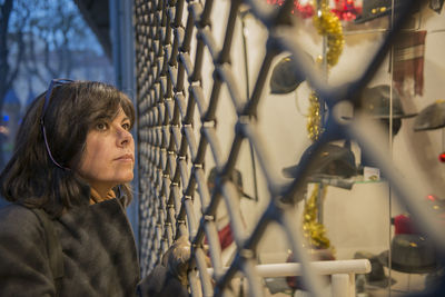 Mature woman doing window shopping in city at dusk