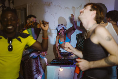 Happy non-binary dj partying with friends at nightclub