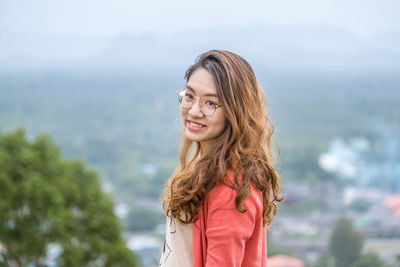 Portrait of smiling woman standing against sea