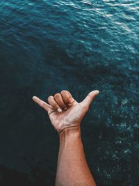 Cropped image of hand against sea