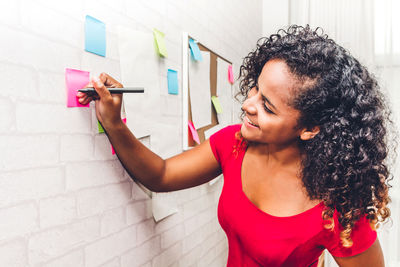 Young fashion designer writing on adhesive notes at home office