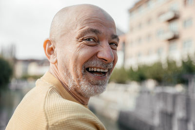Laughing senior man in yellow sweater enjoying time outdoors