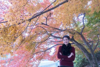 Young woman with umbrella standing in park during autumn