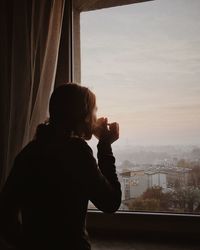 Rear view of man looking through window