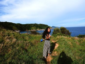 Young woman standing on land against sea