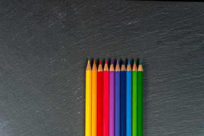 Close-up of multi colored pencils on table against black background