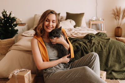 A pretty girl in pajamas rejoices and smiles during the christmas holidays in cozy bedroom interior