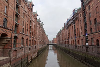 Canal amidst buildings in city against sky