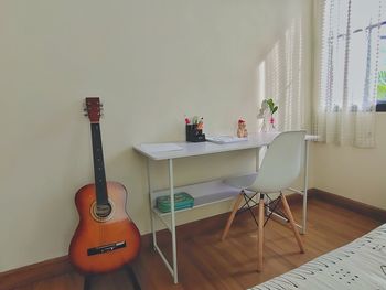 View of guitar on table against wall at home