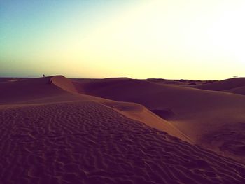 Scenic view of sand dunes against sky at sunset