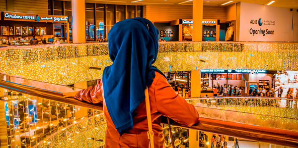 Rear view of man standing at illuminated temple in city at night
