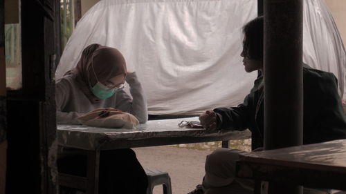 Rear view of children sitting on table