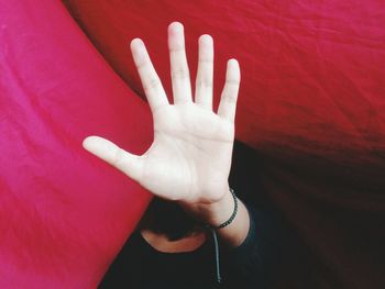 Close-up of man gesturing stop hand sign under pink textile