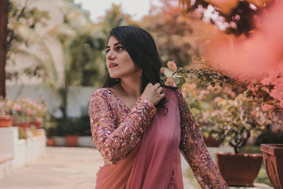 Young woman looking away while standing outdoors