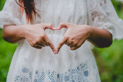Midsection of woman making heart shape with hands