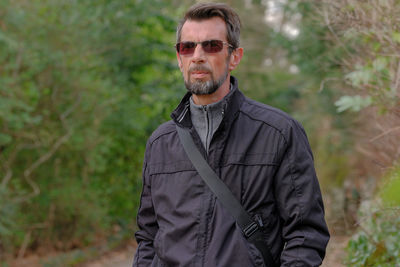 Portrait of man wearing sunglasses standing against plants