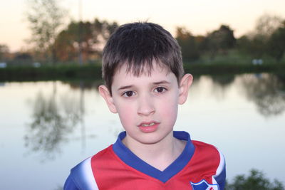 Portrait of cute boy against lake during sunset