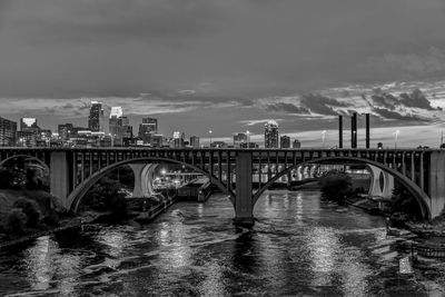 Bridge over river by buildings against sky in city