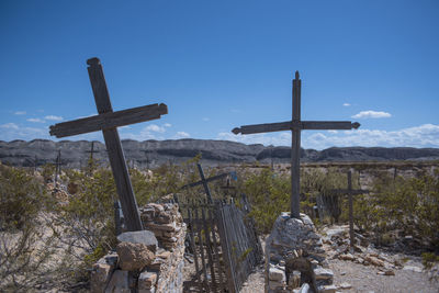 Cross in cemetery against sky