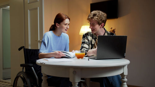 Smiling young couple sitting by desk at home