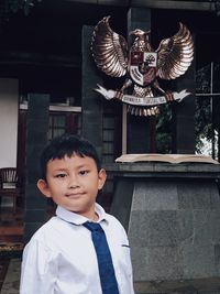 Portrait of smiling boy standing against built structure