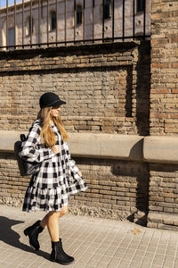 Rear view of woman standing against brick wall