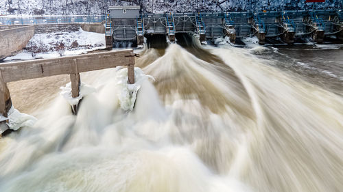 Water is rushing at the dam in winter as spring approaches with extended exposure settings