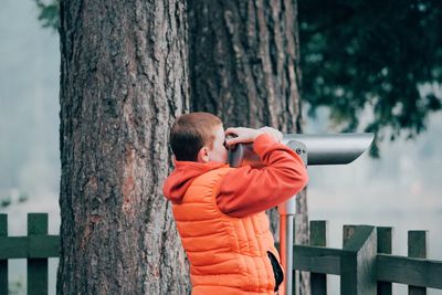 Full length of boy standing on tree trunk