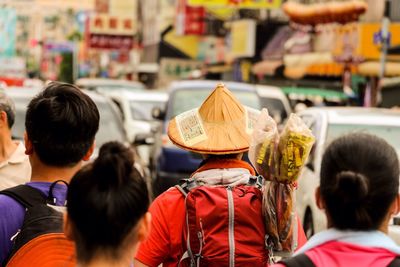 Rear view of men wearing conical hat while walking on city street