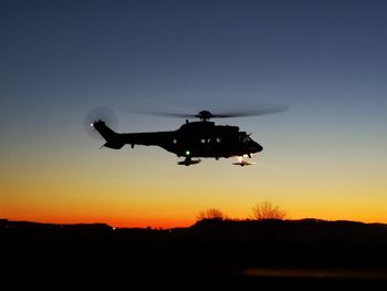 Low angle view of silhouette helicopter against sky during sunset