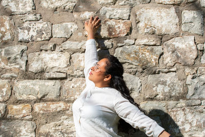 Young woman looking up against wall