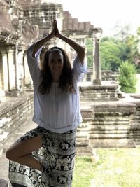 Portrait of smiling young woman exercising in front of built structure