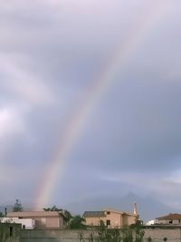 Low angle view of rainbow over buildings against sky